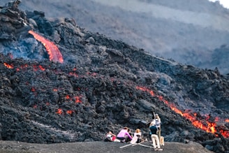 photography of people standing beside lava during daytime