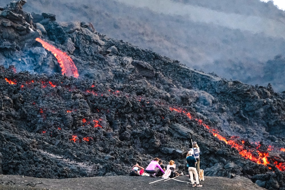 photography of people standing beside lava during daytime
