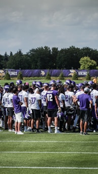 Team huddle showing players with jerseys and helmets, strategizing before a play.