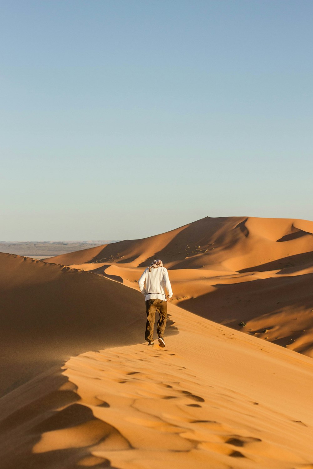 昼間の砂漠を歩く男