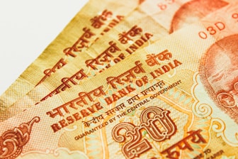 Multiple Indian currency notes close-up with intricate designs and text. The text includes Hindi and English, and there are visible numerals and symbols related to the Reserve Bank of India.