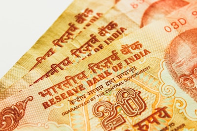 Multiple Indian currency notes close-up with intricate designs and text. The text includes Hindi and English, and there are visible numerals and symbols related to the Reserve Bank of India.