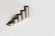 Stacks of coins growing taller on a wooden table symbolizing financial growth.