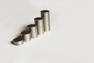 A stack of coins and a calculator on a wooden table.