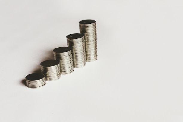 A stack of coins and a calculator on a wooden table.