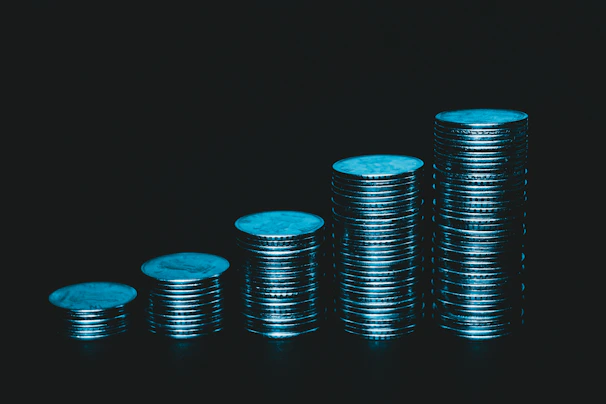 Stack of colorful game currency coins against a neon blue and purple background