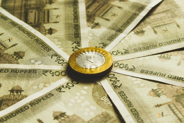 Close-up of Indian Rupee banknotes with a 10 Rupee coin, representing financial support 