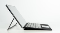 Side view of a thin, lightweight laptop resting on a glass table.