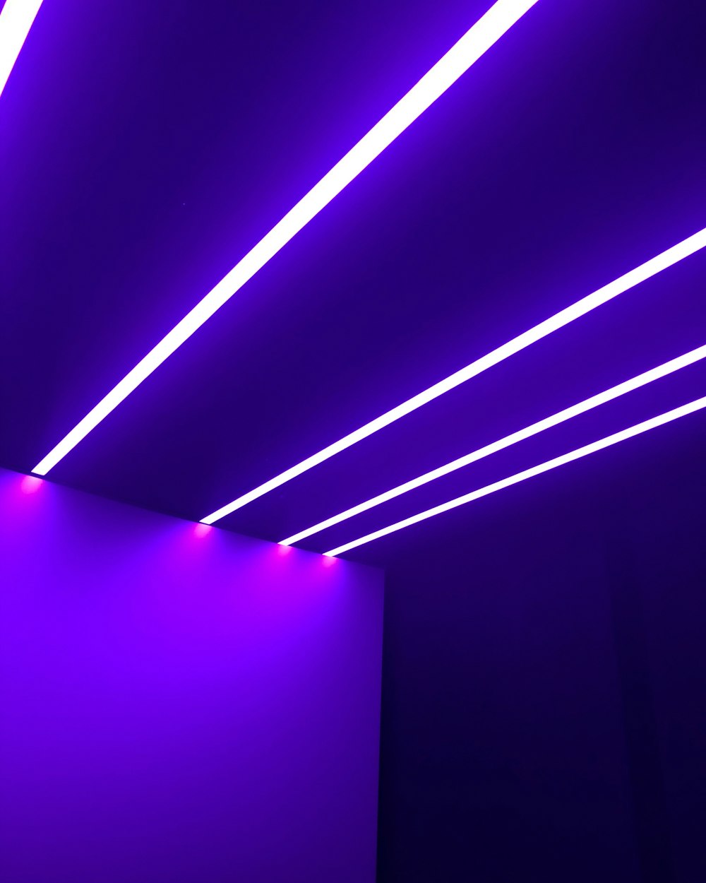 una stanza con illuminazione viola e una parete bianca