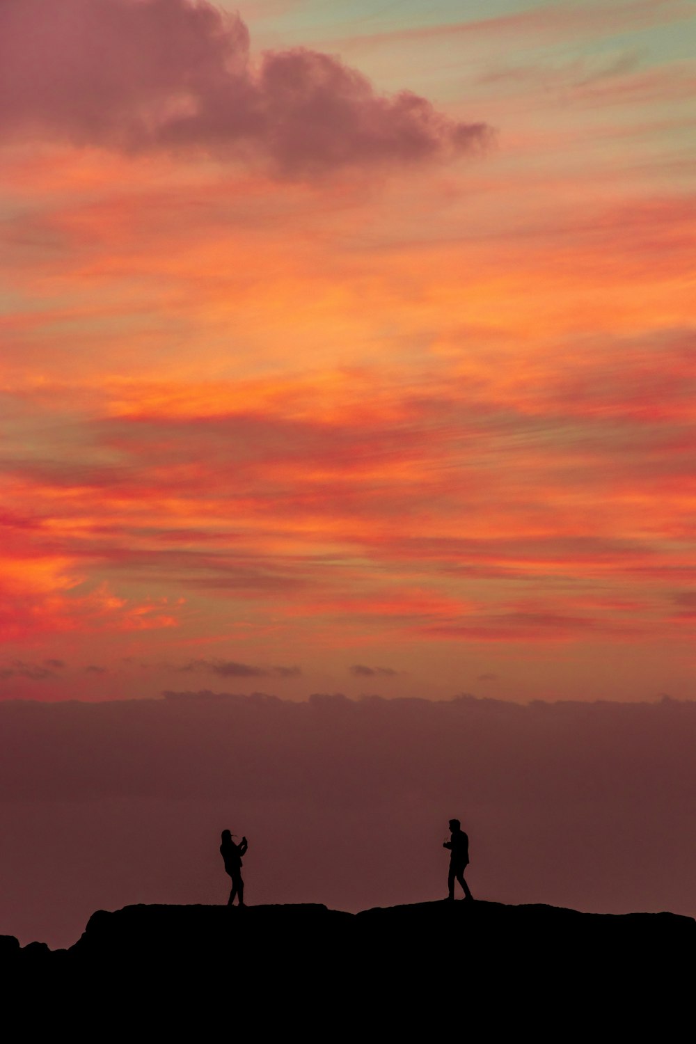 silhouette of two person on rock formation