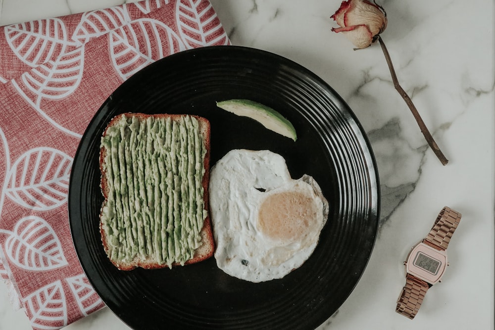 a black plate topped with an egg and toast