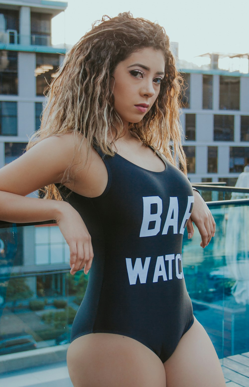 woman wearing one-piece swimsuit leaning on glass wall