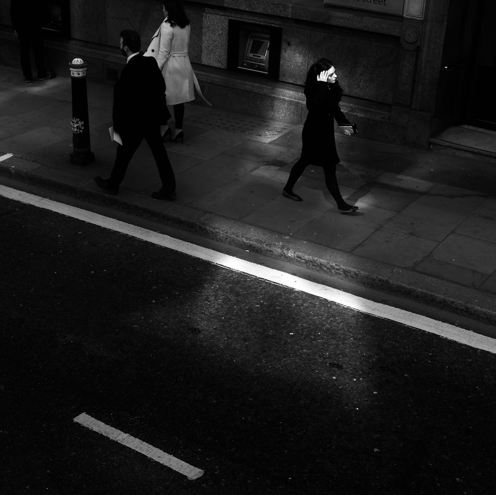 two women and man walking along side of road