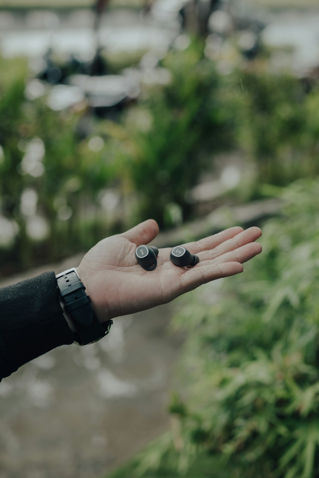 two black wireless earbuds on person's palm