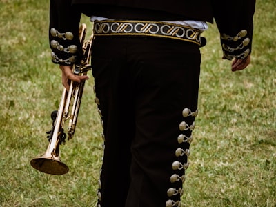 close-up photography of person holding trombone mariachi teams background