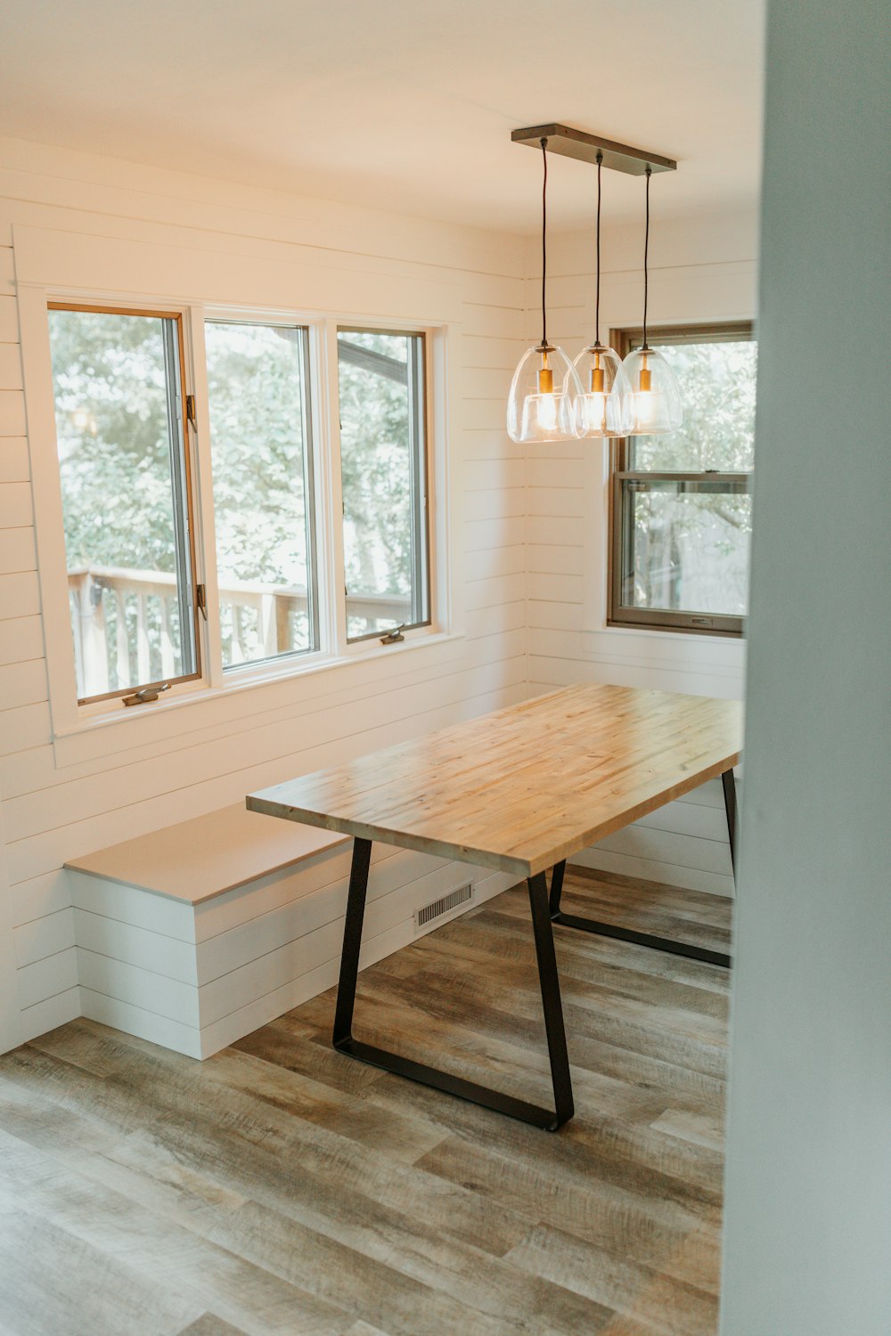 rectangular brown wooden table with black metal base on brown wood parquet floor