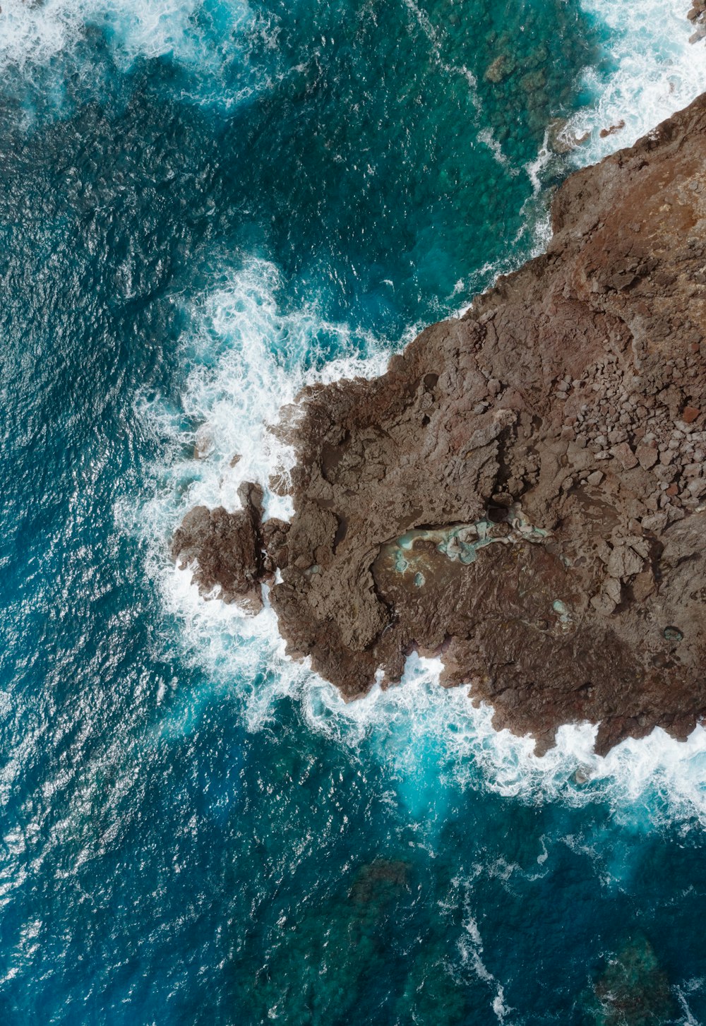 bird's-eye view of brown rocks on body of water