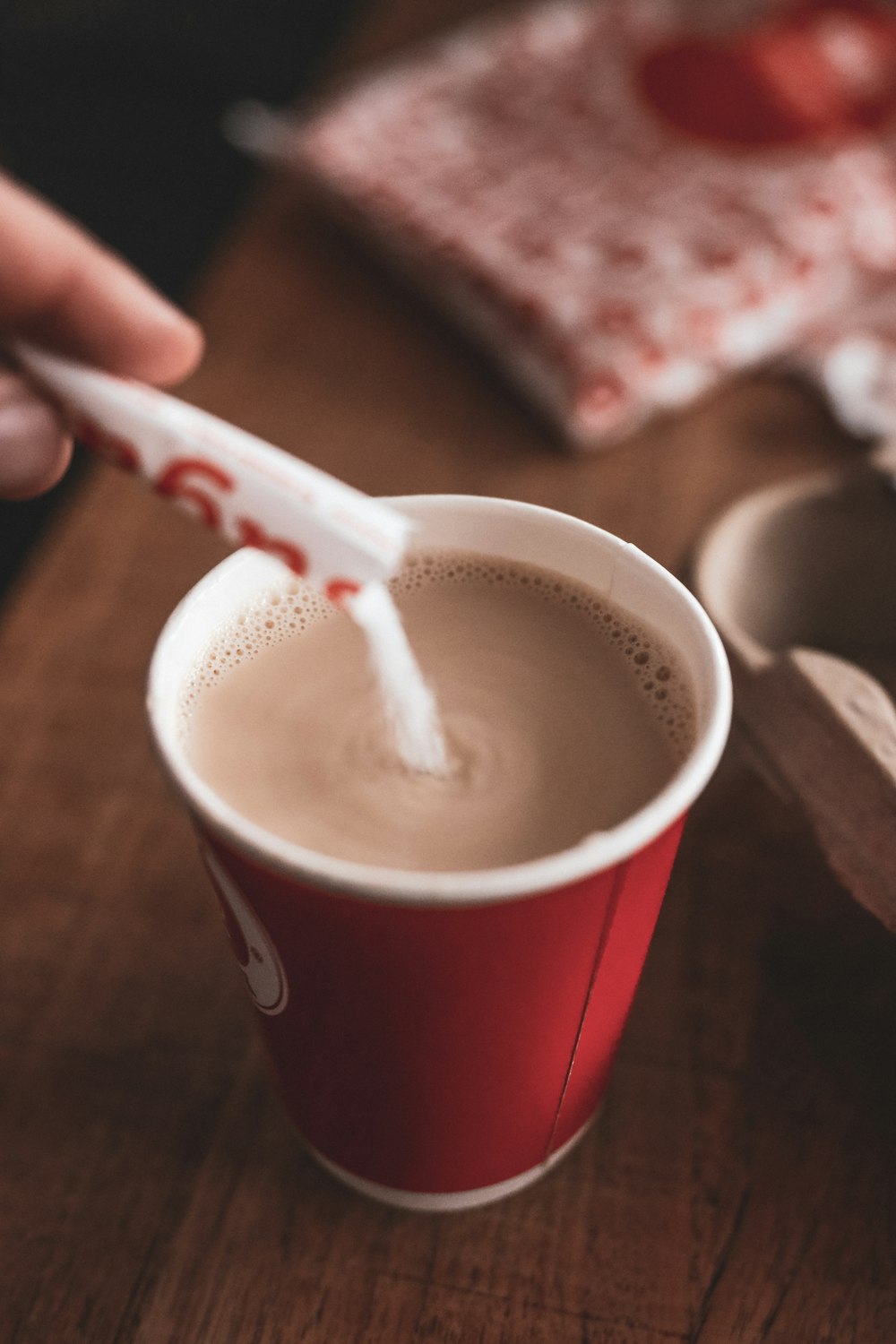 person putting sugar on brown coffee