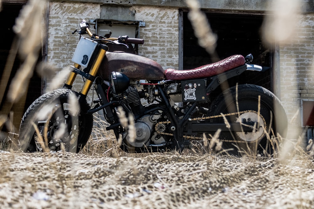 black and brown motorcycle parked besides white and brown concrete house