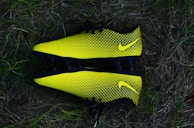 A neatly arranged display of various soccer cleats on a grassy field.