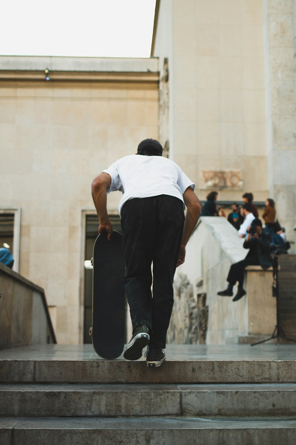 man in white t-shirt and black pants holding skateboard