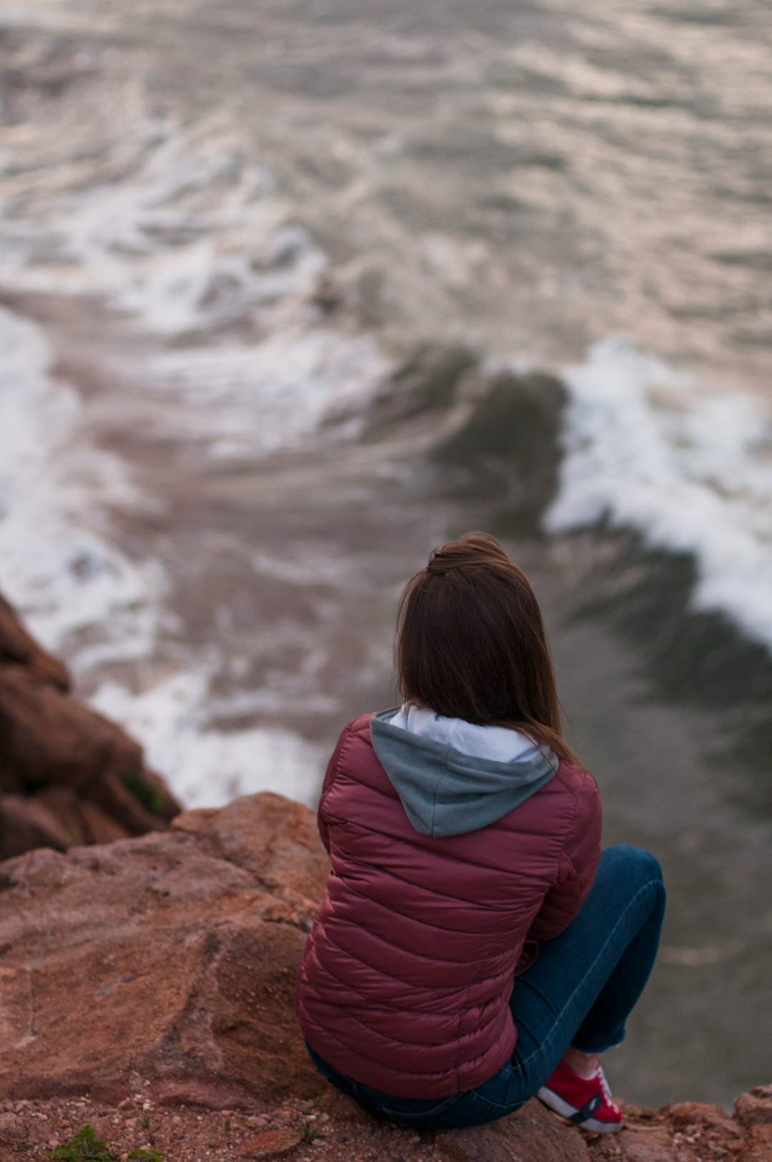 woman sitting on rock at the edge of island during day