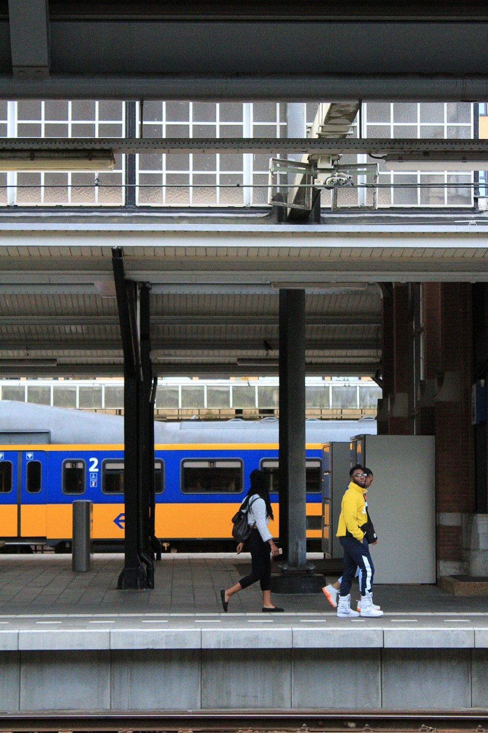 two persons walking beside train rail