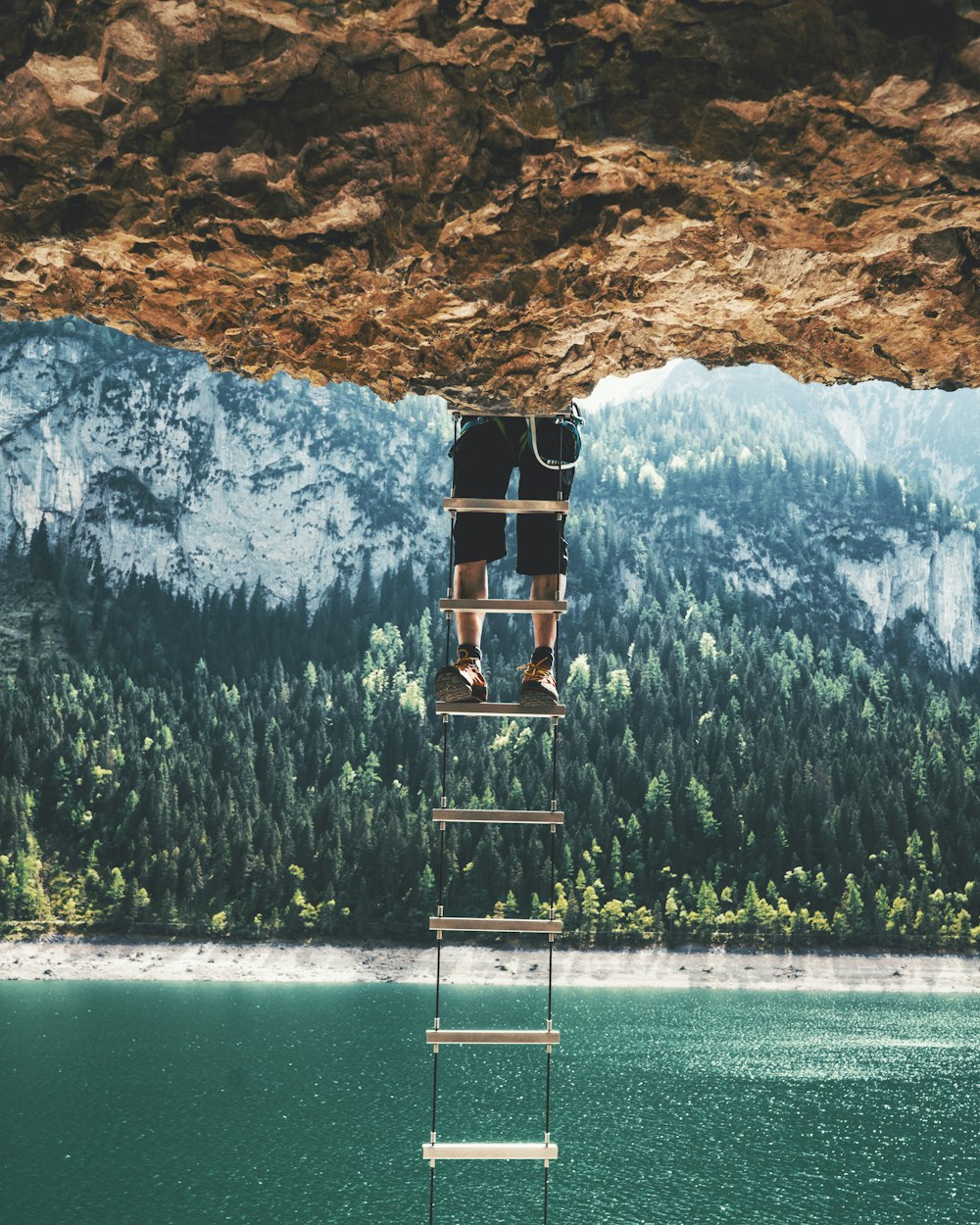 person on ladder near body of water