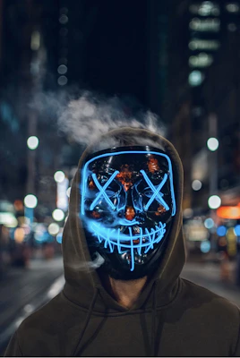 Close-up of a glowing LED mask with intricate cybernetic designs under purple lighting.