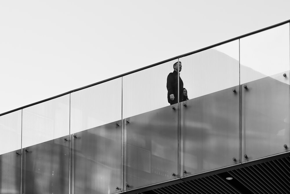 man walking near glass railing