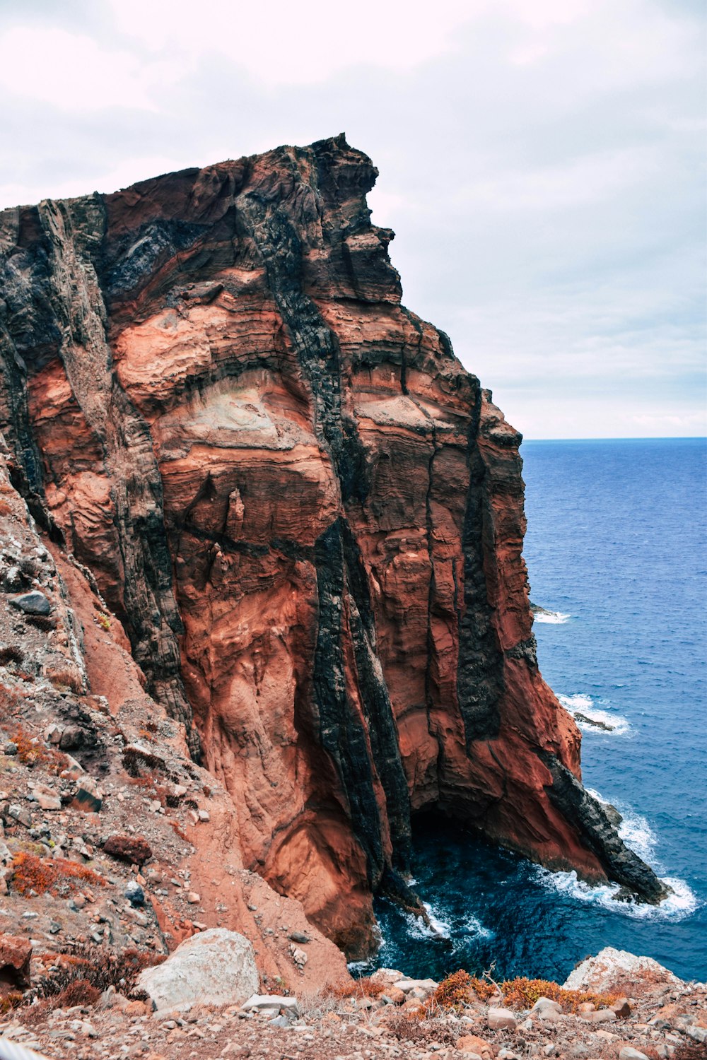 brown rock mountain cliff by the sea during daytime