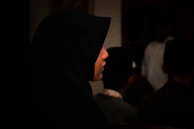 Model showcasing a silk hijab in deep charcoal with soft ambient lighting.