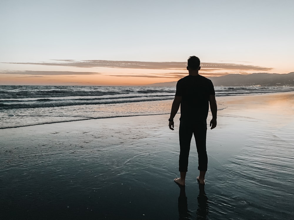 man standing at the beach during sunset