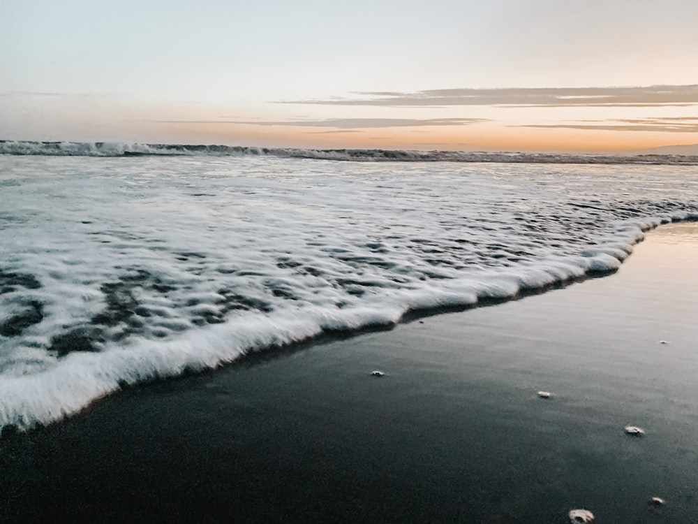 Écume de mer blanche sur le rivage au coucher du soleil