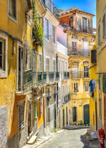 A sunlit narrow alley in Barcelona lined with colorful historic buildings.