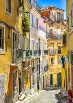 A sunlit narrow alley in Barcelona lined with colorful historic buildings.