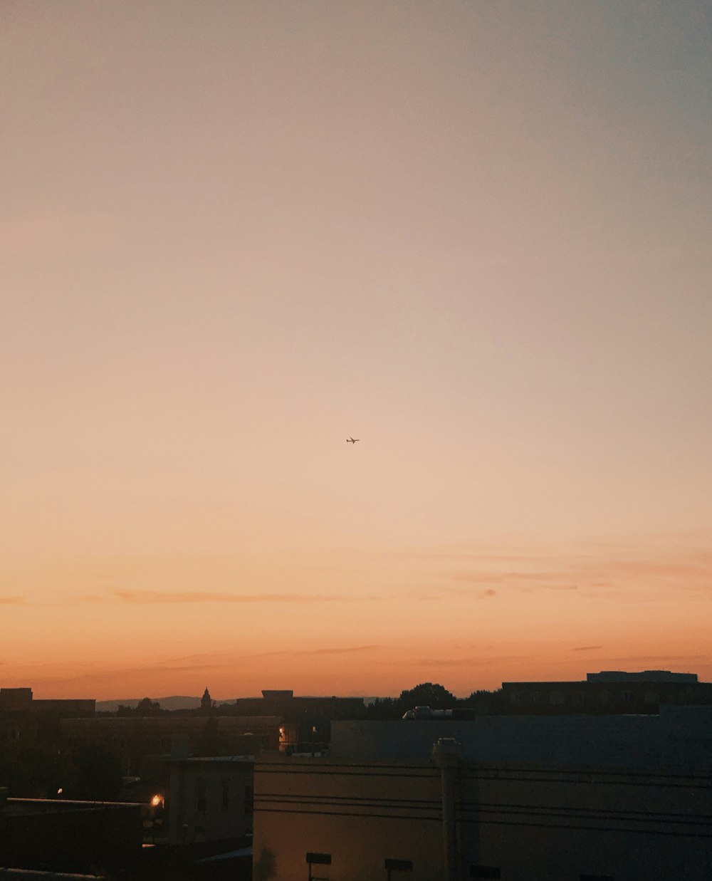 a plane flying over a city at sunset