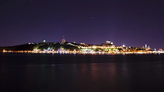 Nighttime shot of La Paz city lights reflecting on the calm bay waters.