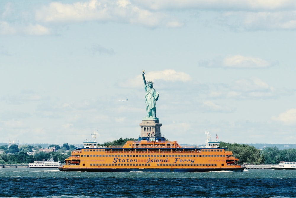 barca gialla sullo specchio d'acqua vicino alla Statua della Libertà sull'isola della Libertà