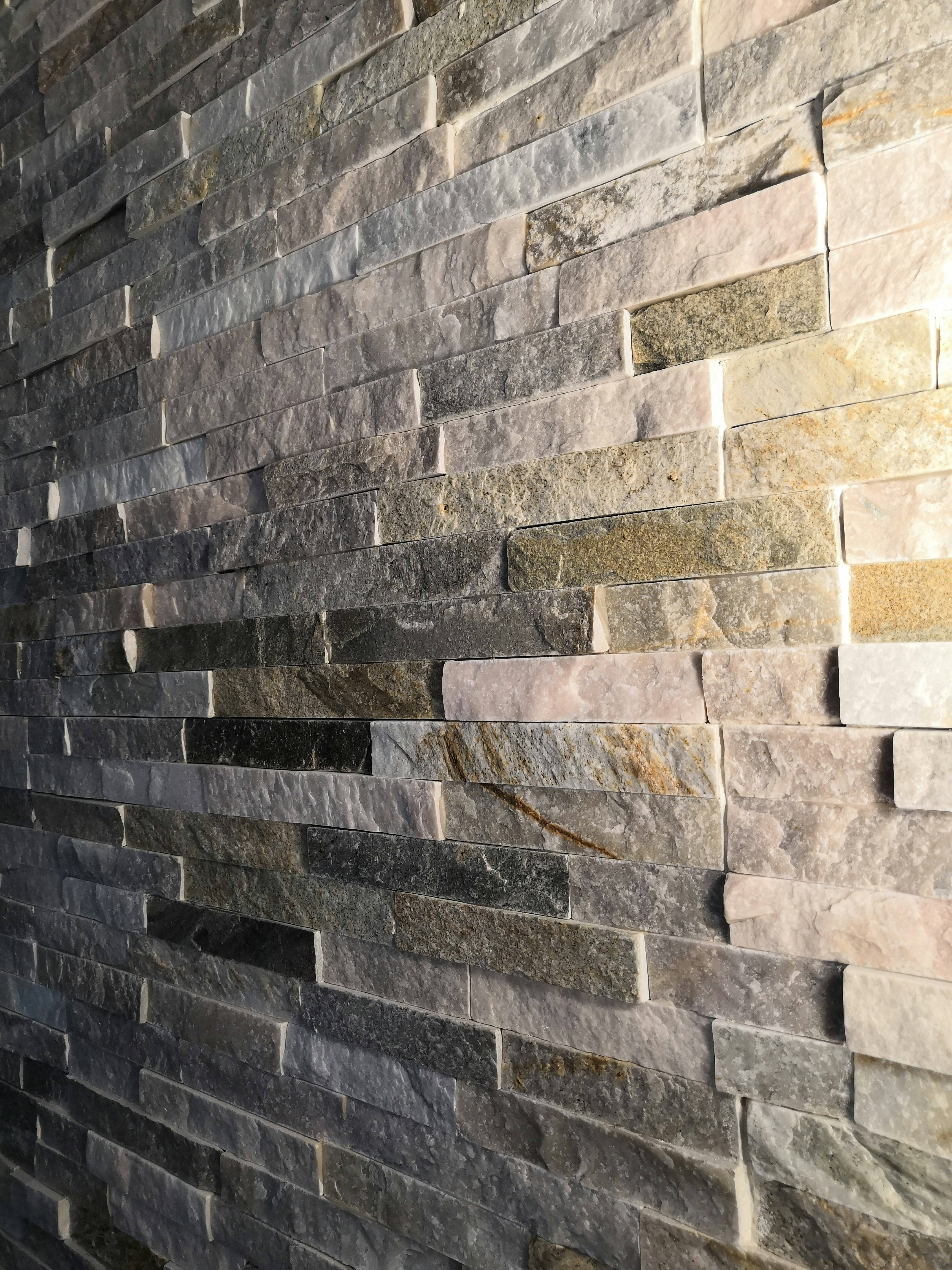 Natural stone wall installation, grey and tan stones, architectural masonry