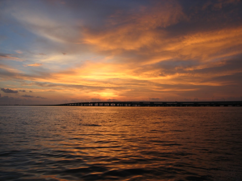 body of water near bridge at golden hour