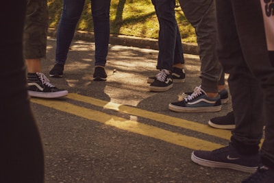 A close-up of running shoes on a trail, with a group of ambassadors in the background sharing a laugh.