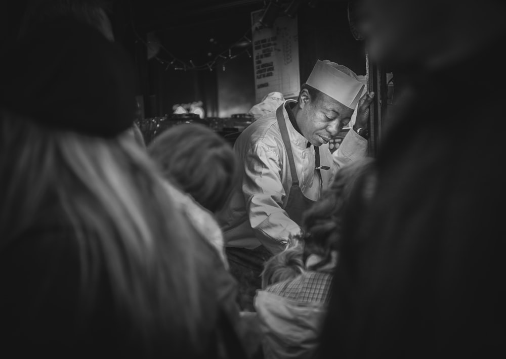 grayscale photography of man wearing hair hat and apron