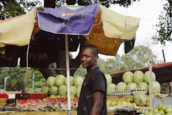 man standing near watermelon fruit stand