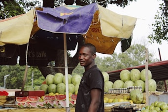 man standing near watermelon fruit stand