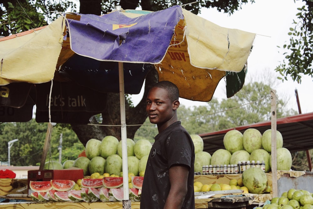 man standing near watermelon fruit stand