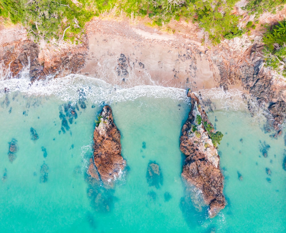 an aerial view of a beach with rocks in the water