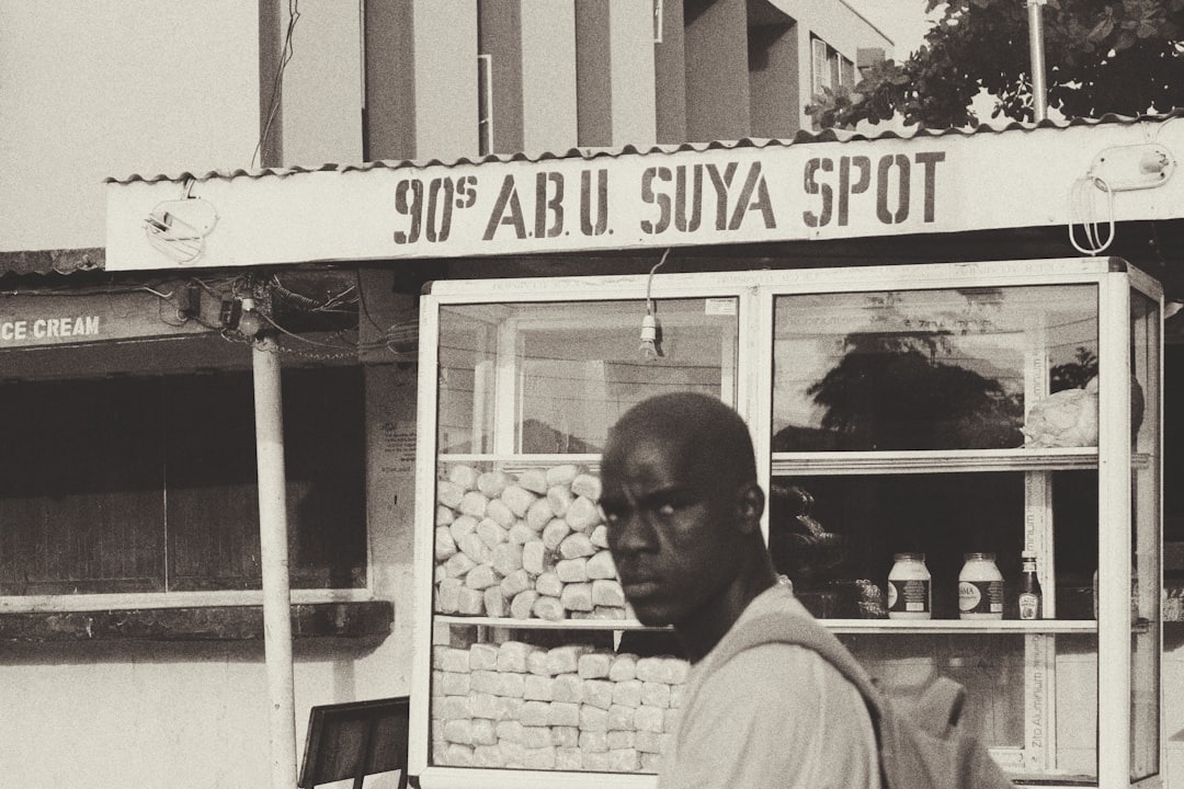 grayscale photo of man standing near food stall