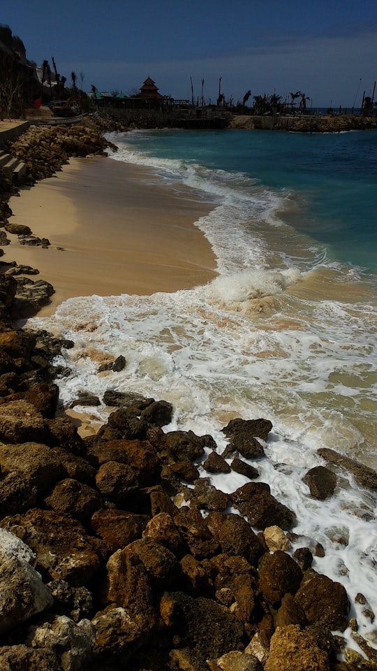 rocks beside body of water at daytime in Jl. Melasti Indonesia