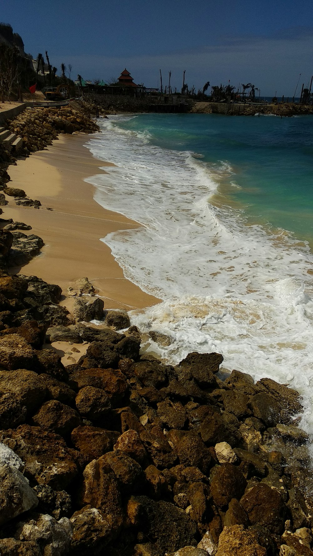 black rocks beside body of water at daytime